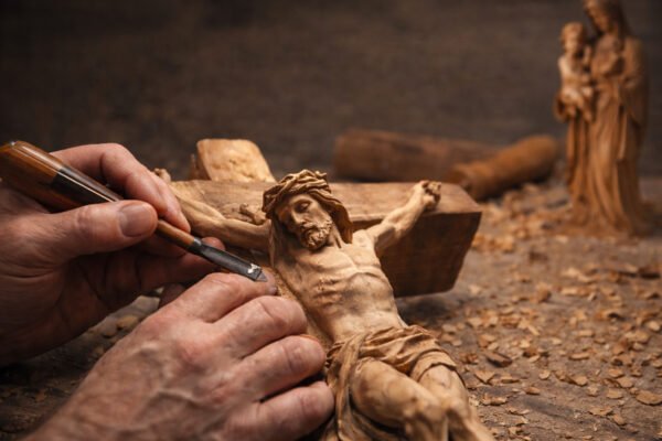 craftsman carving Christian wood art with chisel and knife